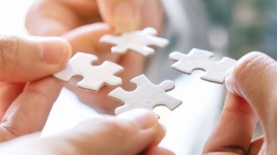 Vier Hände fügen vier Puzzleteile zusammen, Symboldbild Partnerschaften, Key-Work