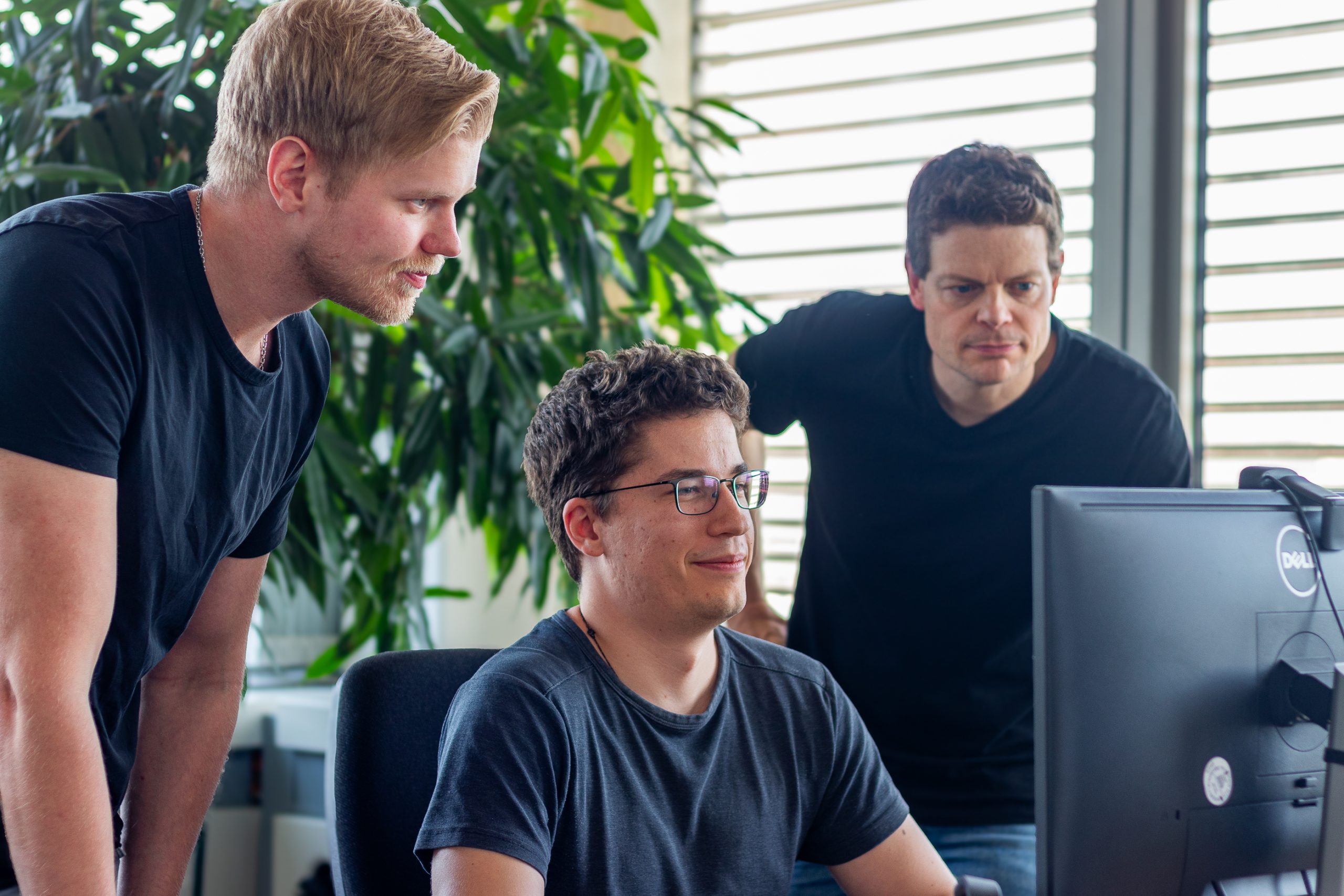 Ein Team von drei Personen vor einem Monitor, Key-Work